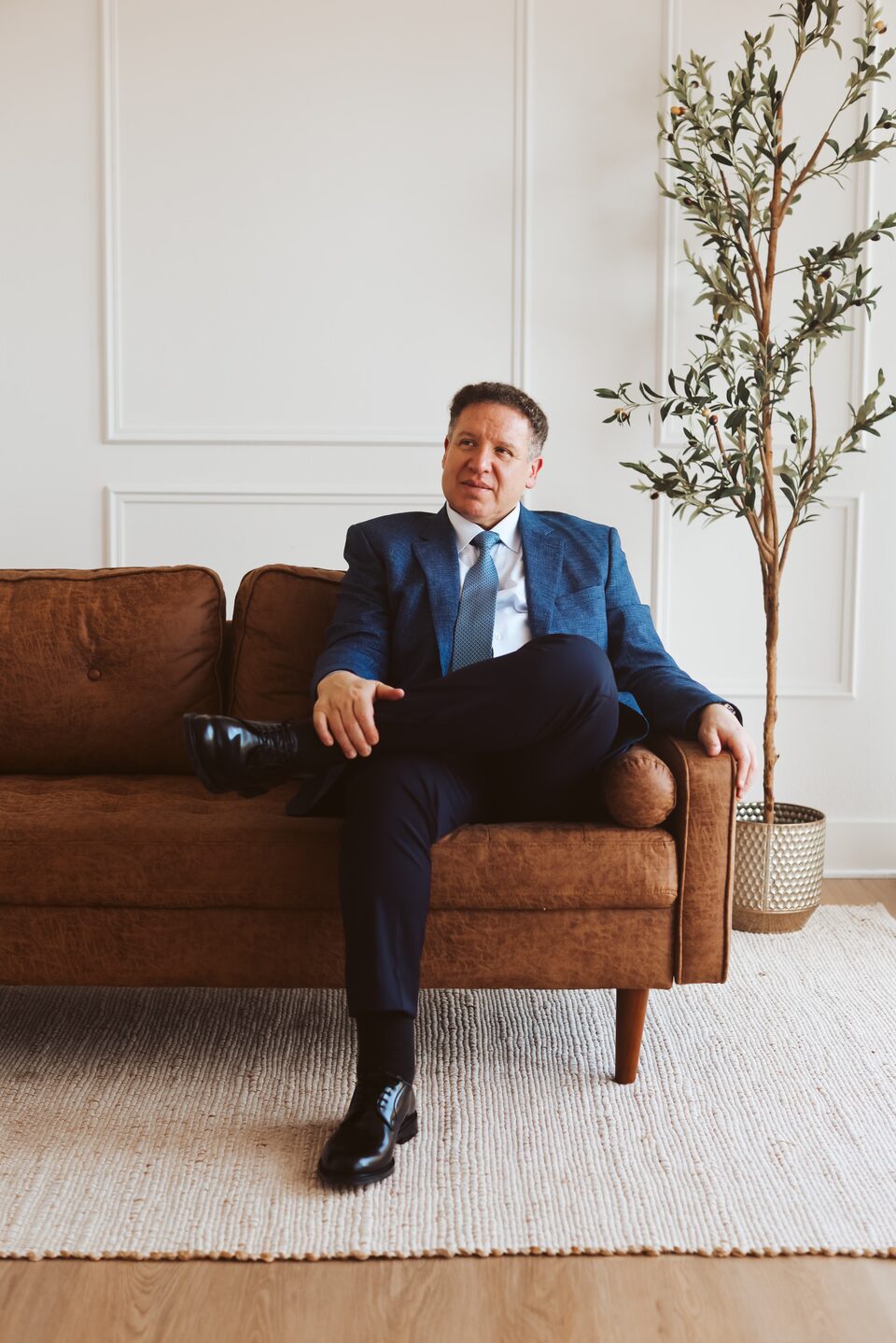 Attorney Carlos Maury, a former U.S. Immigration Judge, seated in a navy suit.