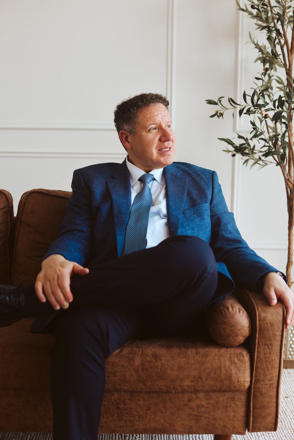 Attorney Carlos Maury reviewing a case file on a leather sofa.