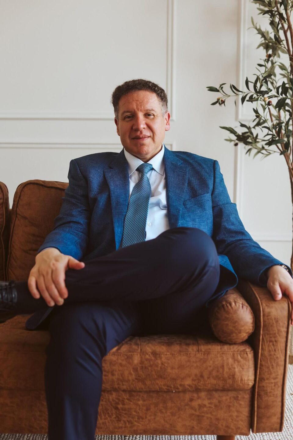 Attorney Carlos Maury, a former U.S. Immigration Judge, seated on a leather sofa.